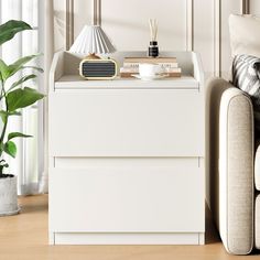 a living room with white furniture and a plant on the side table next to it