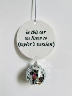 a mirror ball ornament hanging from a string with the words in this car we listen to taylor's version