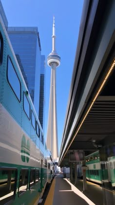 a train traveling down tracks next to a tall building with a spire in the background