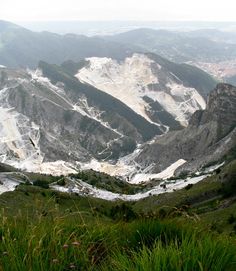 the mountains are covered with snow and green grass in the foreground is a valley