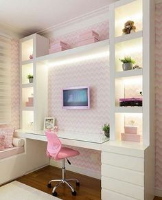 a pink chair sits in front of a desk with a tv on it and shelves