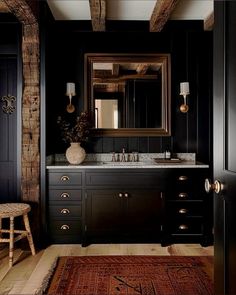 a bathroom with black walls and white counter tops, an antique rug on the floor