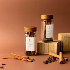 two glass jars filled with cinnamon sticks on top of a wooden block next to other items