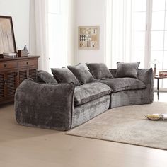 a living room with a large sectional couch and rug on the floor in front of it