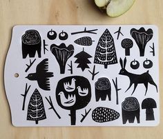 a cutting board with black and white designs on it next to an apple, which has been cut into smaller pieces