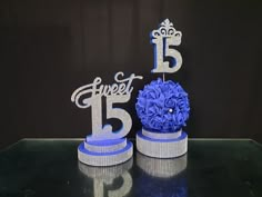 two cake toppers with blue flowers and the number fifteen on them are sitting next to each other