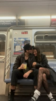 a man and woman are sitting on a subway train together, one is kissing the other's cheek