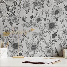 a white desk topped with a laptop computer next to a flower wallpaper covered in black and white flowers