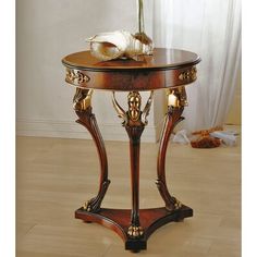 a table with a vase on top of it next to a white wall and wooden floor