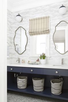 a bathroom with two round mirrors above the sinks and three baskets under the mirror on the counter