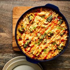 a casserole dish with broccoli and rice in it on a wooden table