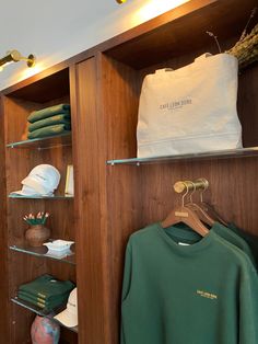 there are many items on the shelves in this closet, including t - shirts and hats