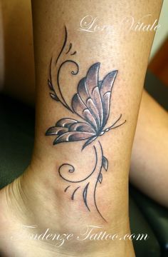 a woman's foot with a butterfly tattoo on the side of her leg,