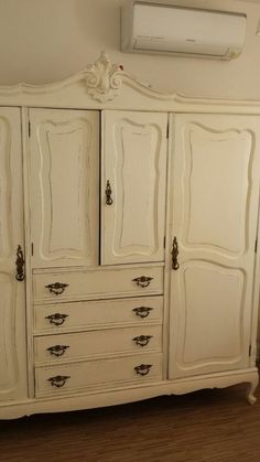 an old white armoire with many drawers