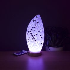 an egg shaped lamp sitting on top of a wooden table next to a remote control