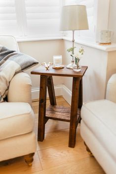 a living room with two white chairs and a small table in front of the window