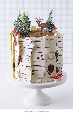 a cake decorated with birch trees and reindeer figurines