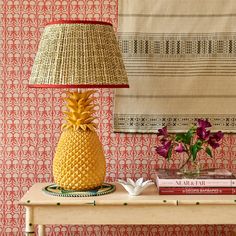 a pineapple lamp sitting on top of a table next to a vase with flowers