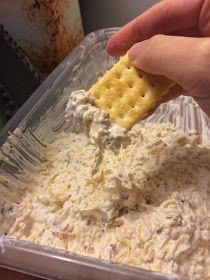 a person dipping crackers into a container of dip