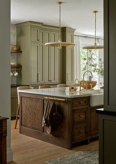 a large kitchen with an island in the middle and two lights hanging from it's ceiling