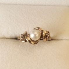 a pearl ring sitting on top of a white cushion