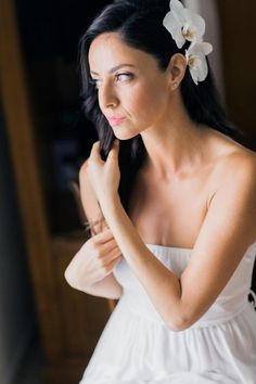 a woman in a white dress is holding her hand on her shoulder and looking off to the side