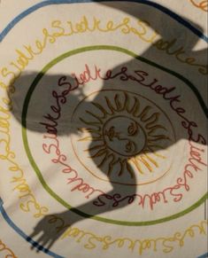 the shadow of a person standing in front of a circular sign with writing on it