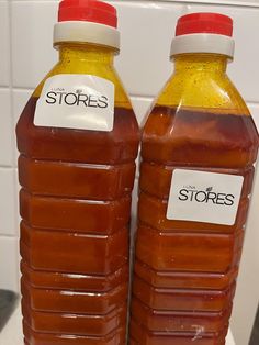 two plastic bottles filled with liquid sitting on top of a white counter next to each other