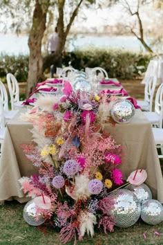 the table is set with flowers and disco balls for an outdoor party or wedding reception