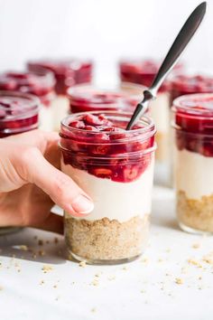 a person is holding a spoon in a jar filled with dessert and oatmeal