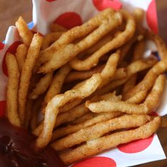 french fries with ketchup in a basket on top of polka dot napkins