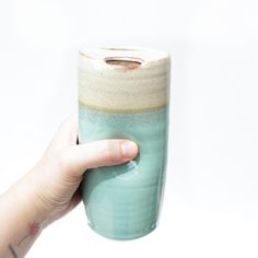 a hand is holding a ceramic cup in front of a white background