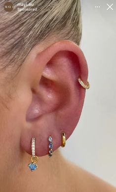 a woman wearing ear piercings with blue and white stones on the inside of her ears