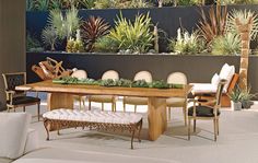 a dining room table with chairs and plants on the wall behind it in front of a couch