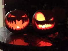 two carved pumpkins sitting on top of a table