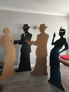 several silhouettes of people standing next to each other in front of a white wall