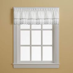 a window with a white valance hanging from it's side next to a yellow wall