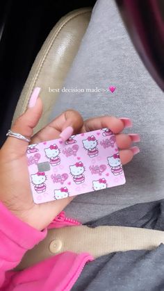 a woman's hand holding a pink hello kitty sticker on her left wrist