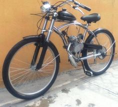 a black and silver motorcycle parked next to a yellow wall with no one on it