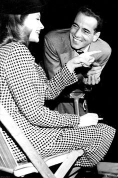 an old photo of a man and woman sitting on a chair smiling at each other