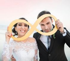 a bride and groom holding up an infinite sign