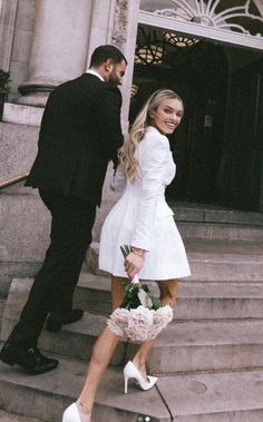 a man and woman are walking down the steps holding hands with each other in front of a building