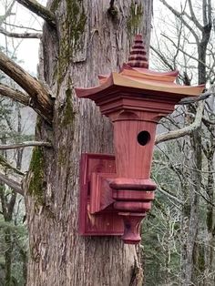 a red bird house on the side of a tree