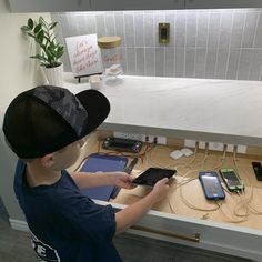 a young boy standing in front of a counter holding an electronic device