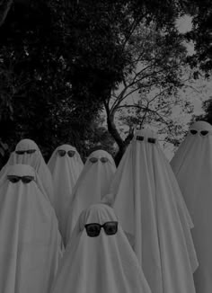 several white ghost like figures with sunglasses on their heads and eyes are standing in a row