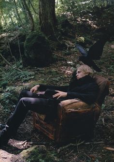 a man sitting in a chair with a crow on his head