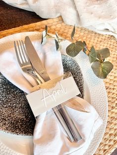 an empty plate with silverware on it next to a place card and some flowers