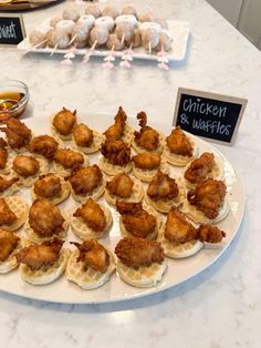 chicken and waffles are displayed on a table with other food items in the background