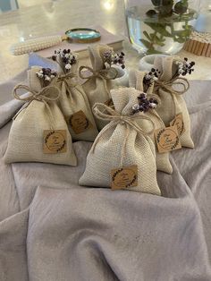 three bags filled with lavender flowers sitting on top of a table next to a vase