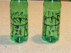 two green water bottles with graffiti written on them